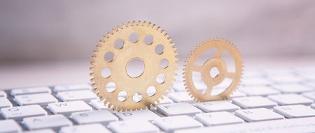 Metal gear wheels on a computer keyboard.の写真素材