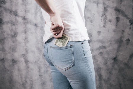 Woman hand putting money in jeans pocketの写真素材