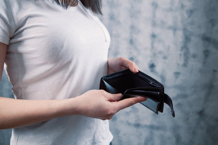a young woman takes her wallet out of her pocket on a gray background