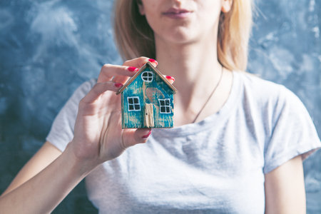 girl holding a small house in her handの写真素材