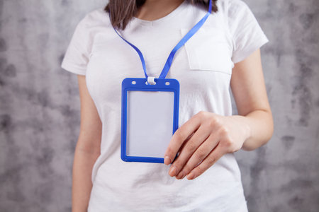 young girl holds an ID card on a gray background