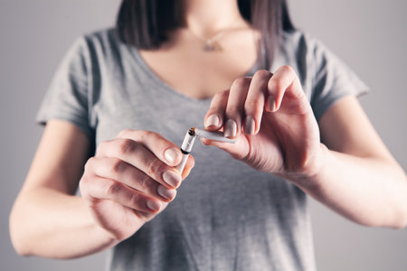 young girl breaks a cigarette on a gray backgroundの写真素材