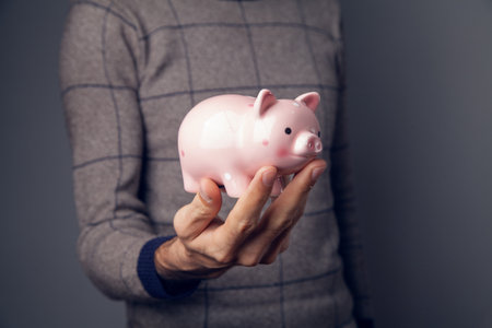 man holding piggy bank on gray background