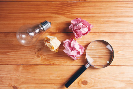 crumpled papers, light bulb and magnifying glassの写真素材