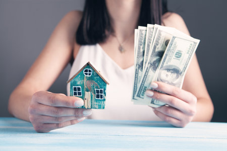 young woman holding house and moneyの写真素材