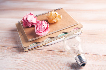notebook, pen, crumpled papers and a light bulb on the tableの写真素材