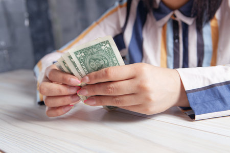 woman counting money in front of the tableの写真素材
