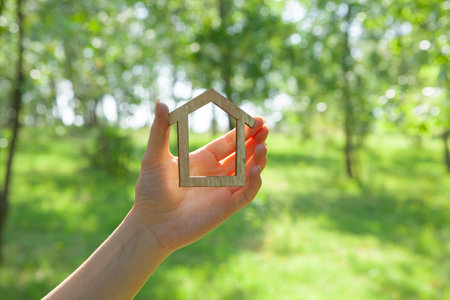 holding a house in his hand on the background of natureの写真素材