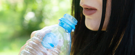 girl drinking water from a bottle in the parkの写真素材