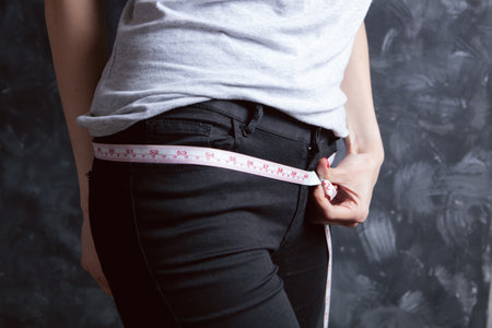 young girl measuring her waist with a measuring tapeの写真素材