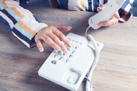 young woman dialing by home phoneの写真素材