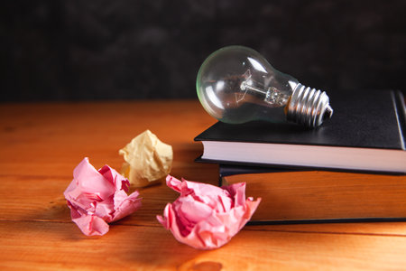 light bulb, crumpled papers and notepad on the tableの写真素材