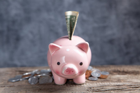 coins and a piggy bank with a dollar bill on the tableの写真素材