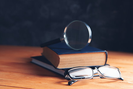 books, magnifying glass and glasses on the tableの写真素材