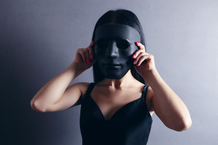 a young girl stands in an anonymous maskの写真素材