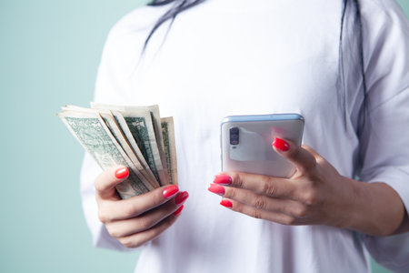 woman holding banknotes and phoneの写真素材