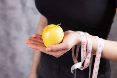 girl holding apple and measuring tapeの写真素材
