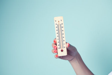 female hand holding a wooden thermostatの写真素材