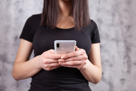 a young girl stands with a phoneの写真素材