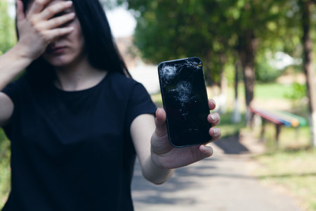 holding a broken phone in the parkの写真素材