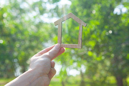 holding a house in his hand on the background of natureの写真素材