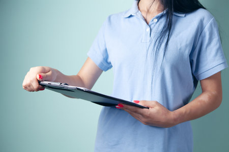 young woman stands holding a tablet for papersの写真素材