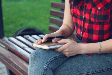 a young girl sitting on a bench makes notes in a diaryの写真素材