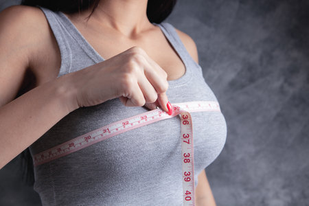 young girl measures her breastsの写真素材