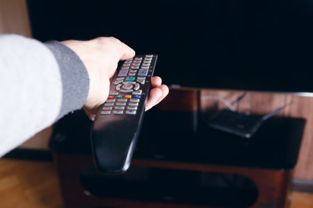 a man's hand holding a tv remote