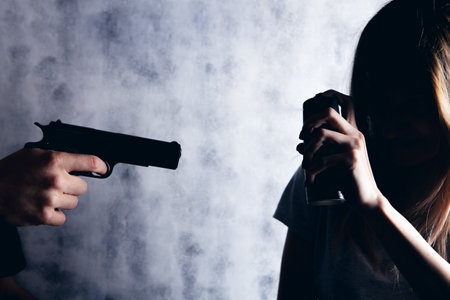 woman defend herself with a spray can from an armed manの写真素材