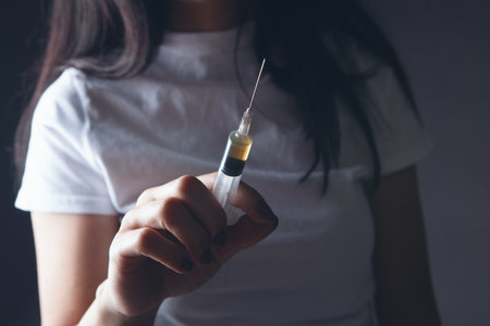 young woman holding a syringe in her handの写真素材