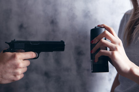 woman defend herself with a spray can from an armed man