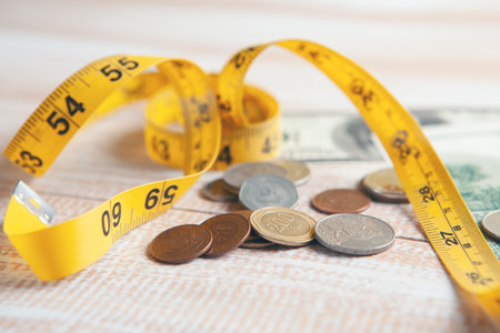 coins, dollar bills and measuring tape on the tableの写真素材