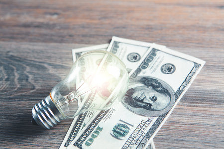 light bulb and money on the tableの写真素材