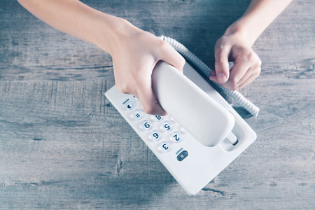 a woman dials a number on a home wired phoneの写真素材