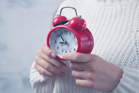 young woman holding an alarm clock