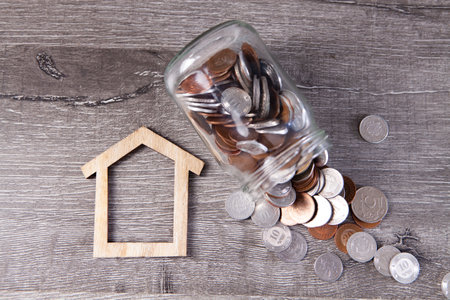 a bank with coins and a house on the tableの写真素材