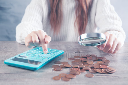 a magnifying glass examines money and calculates on a calculator