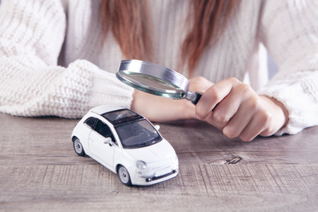 woman with a magnifying glass looks at the car. car search conceptの写真素材