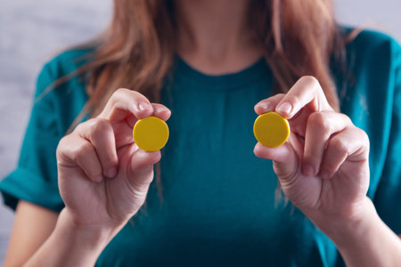 young woman holding yellow pillsの写真素材