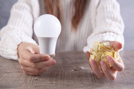 Young woman holding a lamp and crumpled paper