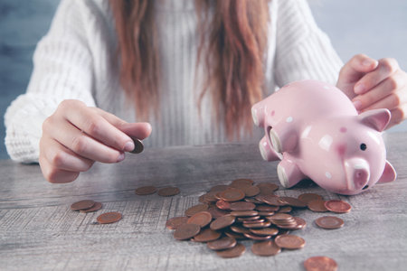 woman counting coins on the table and next to a piggy bankの写真素材