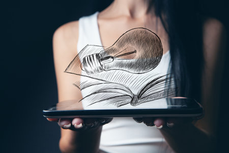drawn light bulb and book. woman holding tabletの写真素材
