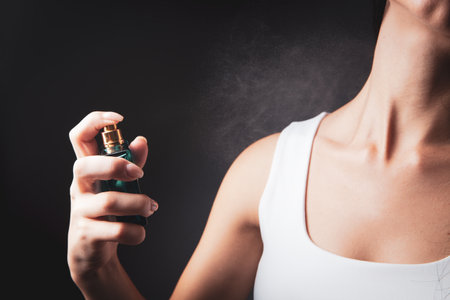 womens uses perfume on themselves on gray background