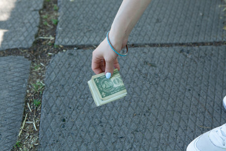 the girl in the park picks up money from the groundの写真素材