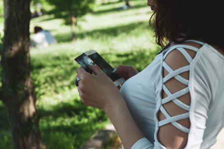woman holding phone and credit card in the parkの写真素材