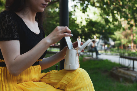 woman pulls phone out of bag in the park