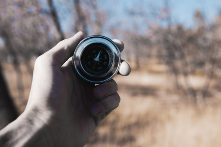 hand holds a compass on the background of natureの写真素材