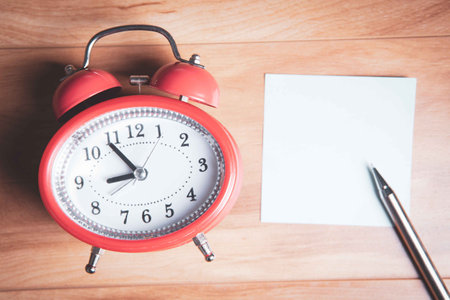blank note sheet with alarm clock on the table