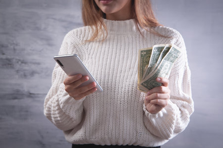 girl holding a phone and moneyの写真素材